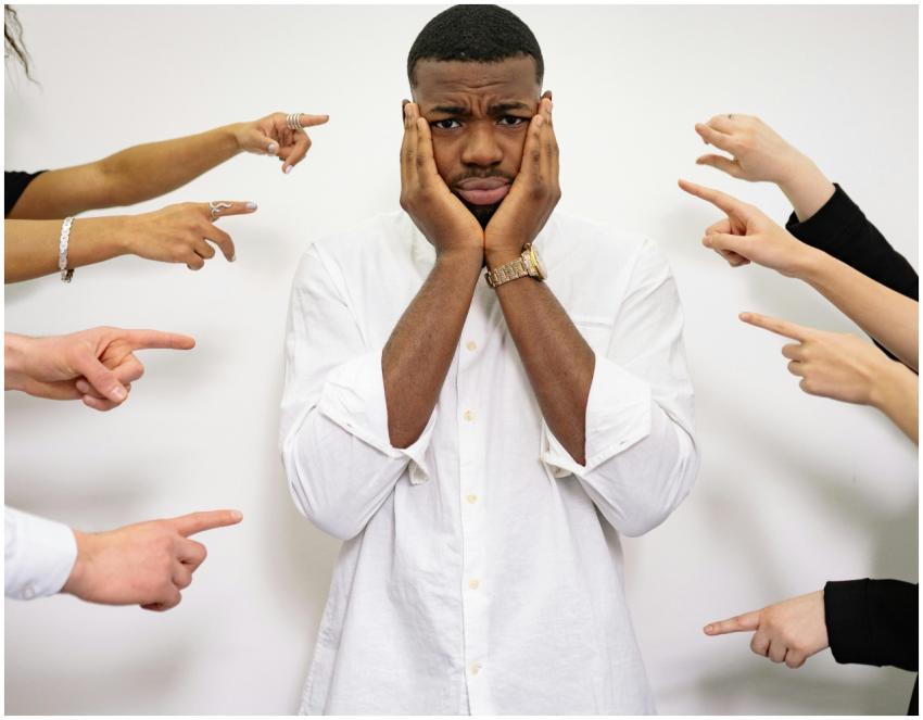 Worried man surrounded by pointing fingers, symbol