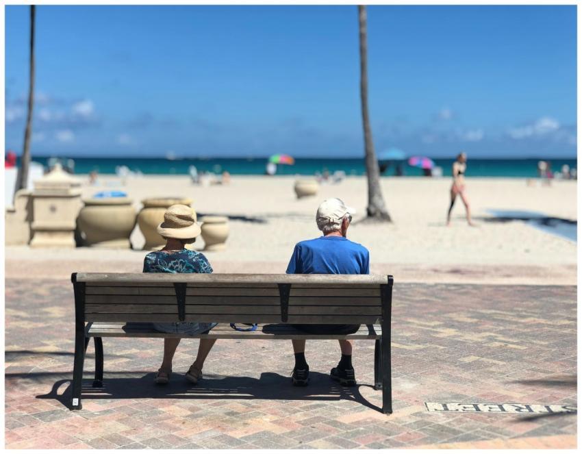 Senior couple sitting on a bench enjoying a sunny