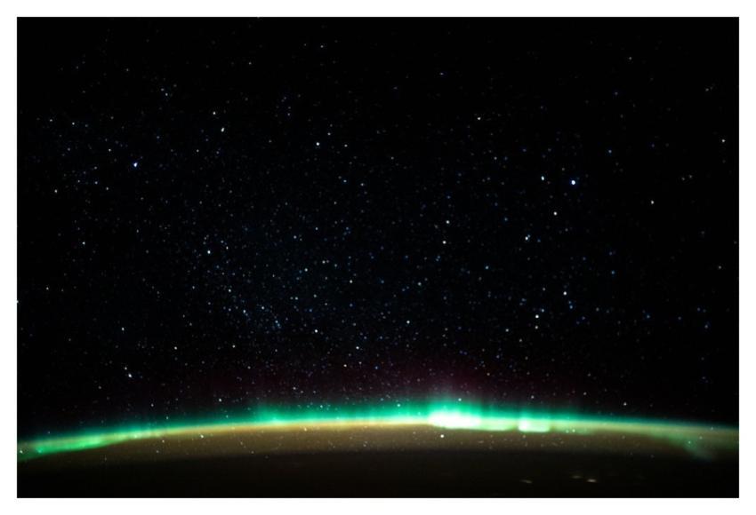 An aurora blankets the Earth beneath a celestial n