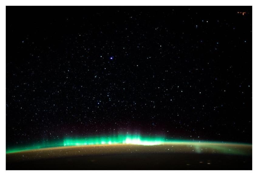 An aurora blankets the Earth beneath a celestial n