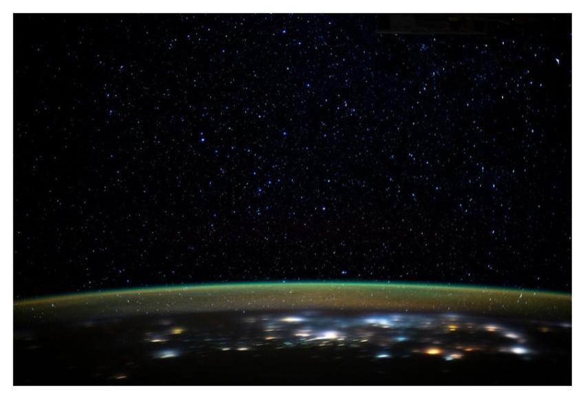 Stars glitter in the night sky above Earth's atmos