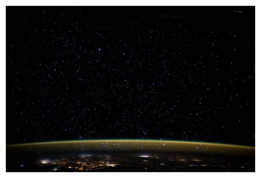Stars glitter in the night sky above Earth's atmos