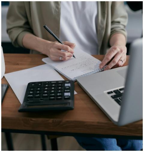 A woman writes financial calculations in a noteboo