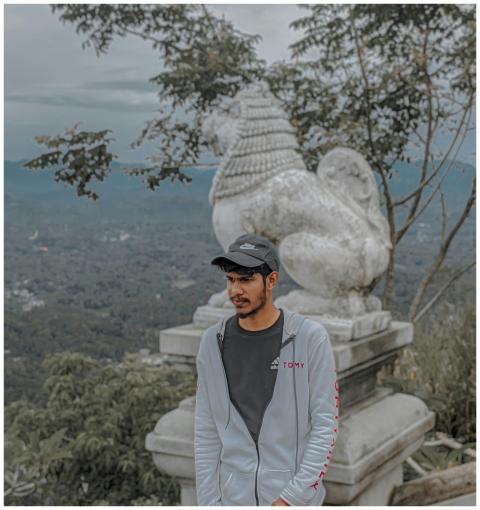 Young man posing by a stone lion statue with a sce