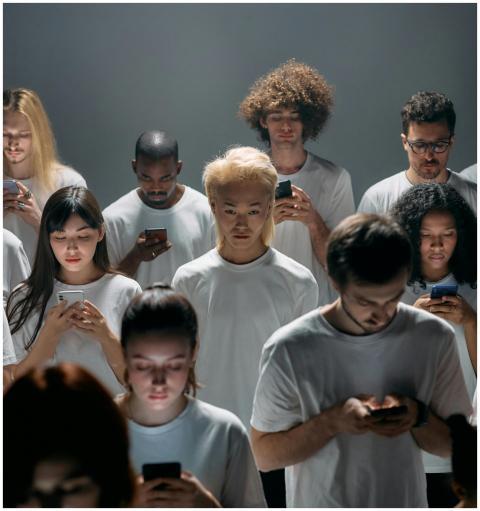 Diverse group of adults focused on smartphones, de