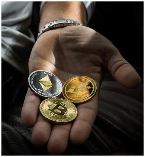 Hand holding Bitcoin, Ethereum, and Ripple coins r
