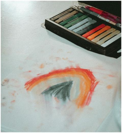 Artistic pastel crayons with a rainbow drawing on