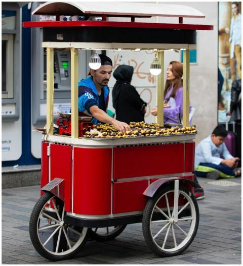 Street vendor with a red cart selling roasted ches