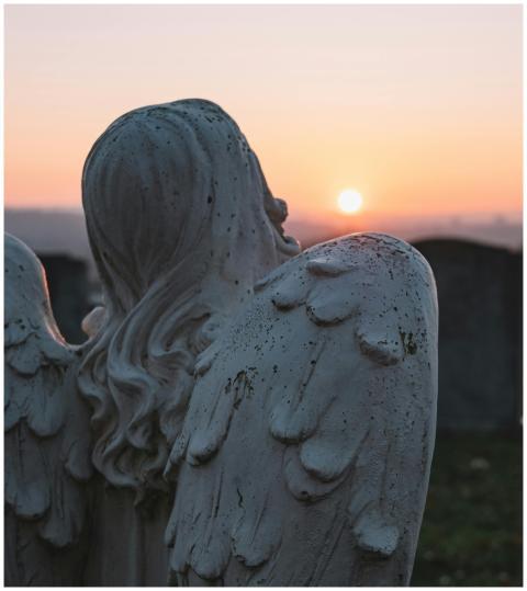 A contemplative angel statue in a cemetery, facing