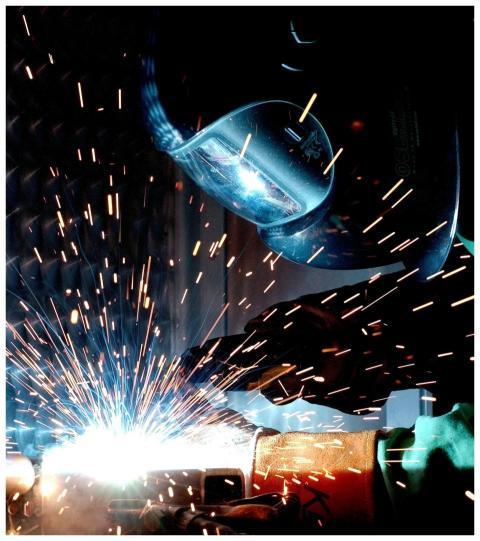 A focused welder works with metal in an industrial