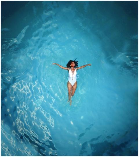 An African American woman in a swimsuit floats pea