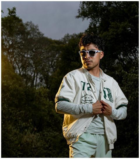 Confident man in a white jacket and sunglasses pos