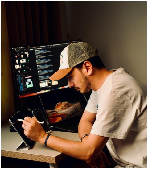Young man in baseball cap working with devices in