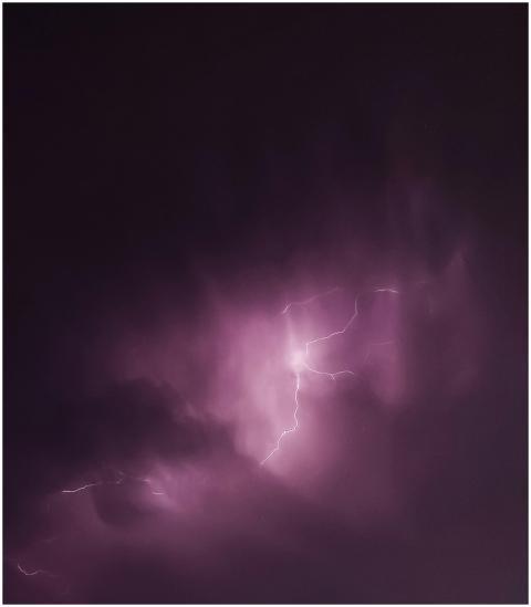 Purple lightning bolts illuminate a moody night sk