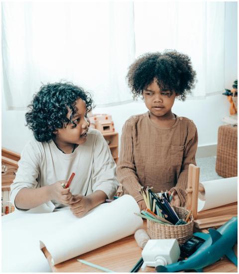Two children drawing together indoors, sharing art