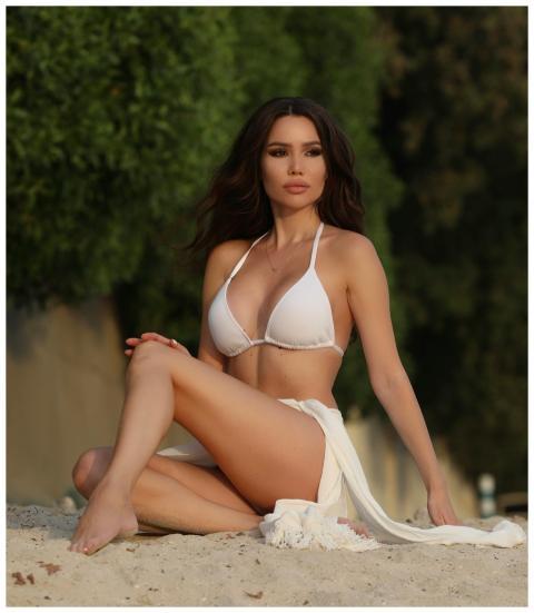 Elegant woman in a white bikini poses on a sunny b