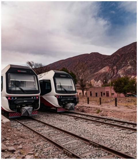Two modern trains on tracks with mountains in Maim