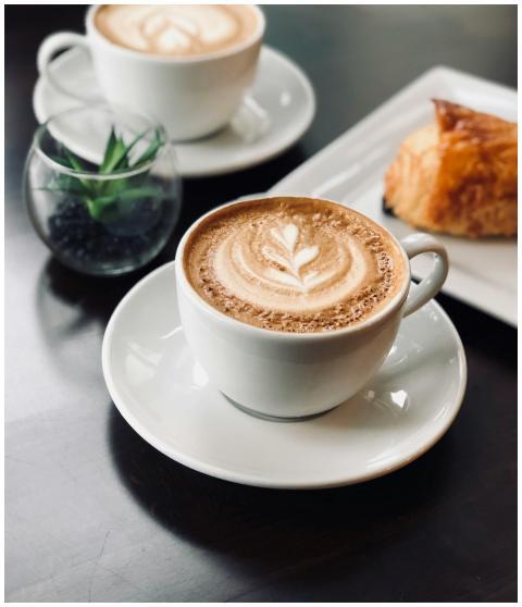 Delicate latte art in a café setting with a pastry