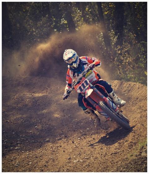 Motocross rider speeding on a dirt track, creating