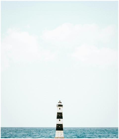 A solitary lighthouse stands against a clear sky a