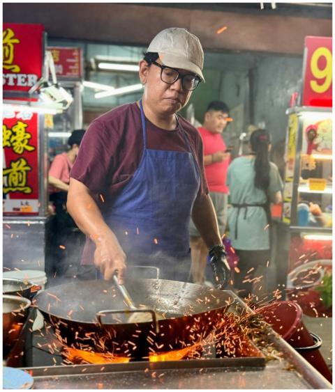 A street food vendor cooking at a vibrant night ma