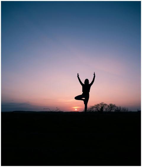 Yoga practitioner silhouetted against a serene sun