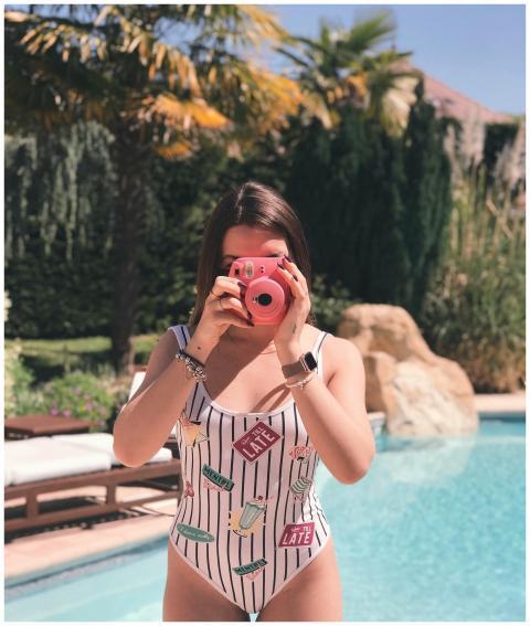 Woman holding an instant camera by a pool under br