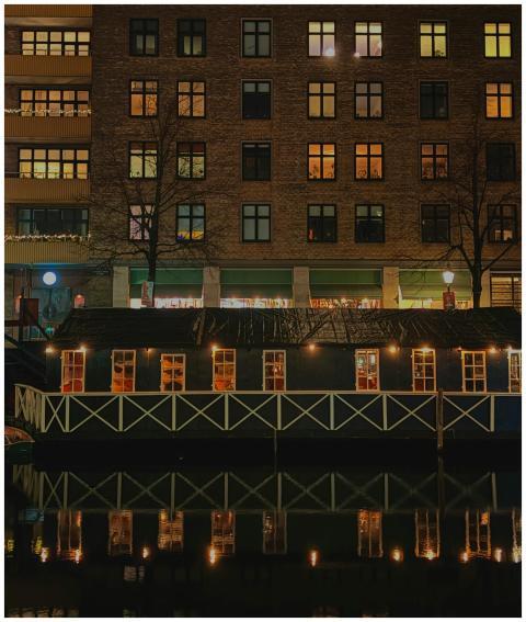Illuminated riverside building reflecting in water