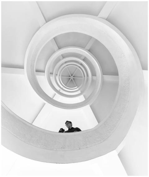 Monochrome image of a spiral staircase with a pers