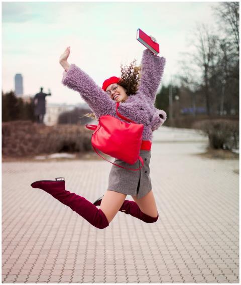 A fashionable young woman jumping with joy outdoor
