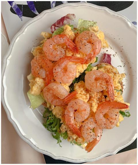 Delicious scrambled eggs topped with shrimp on a w