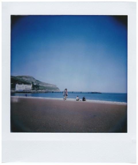 Scenic beach photo featuring tourists, blue sky, a
