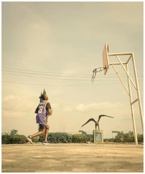 Young athlete playing basketball outdoors in Eduna