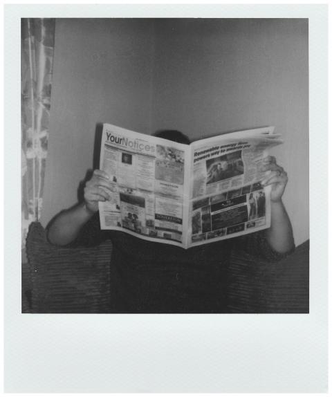 Person reading a newspaper at home in a vintage bl