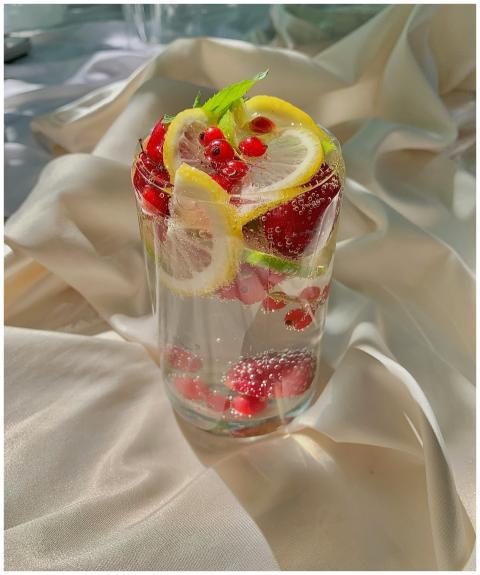Clear glass of citrus berry detox water with lemon