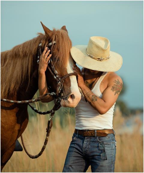 A man in a cowboy hat tenderly embraces his horse
