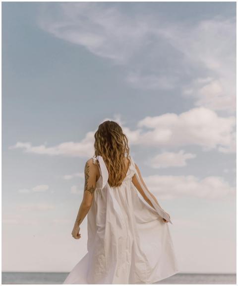 A woman in a white dress stands alone, gazing at t