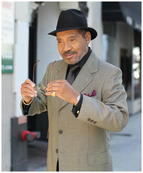 An elegant senior man in a formal coat and fedora