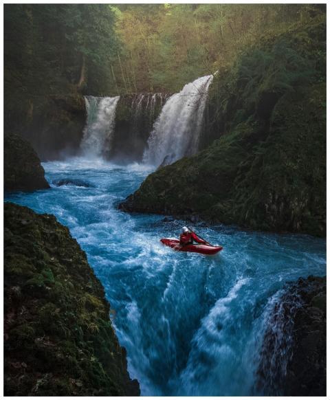 Dramatic scene of a man kayaking down waterfall su