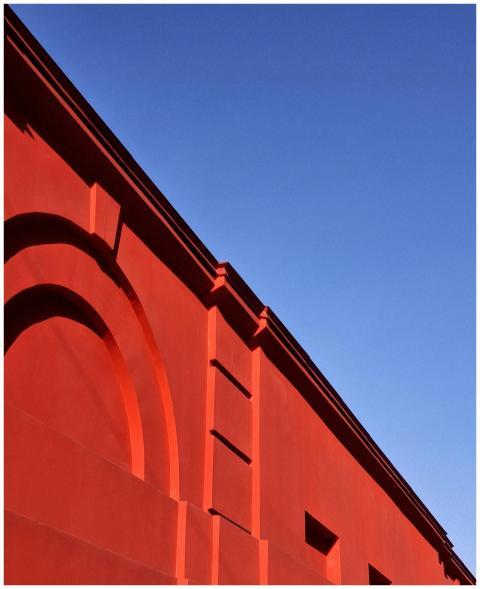 Sunlit red building facade against a clear blue sk