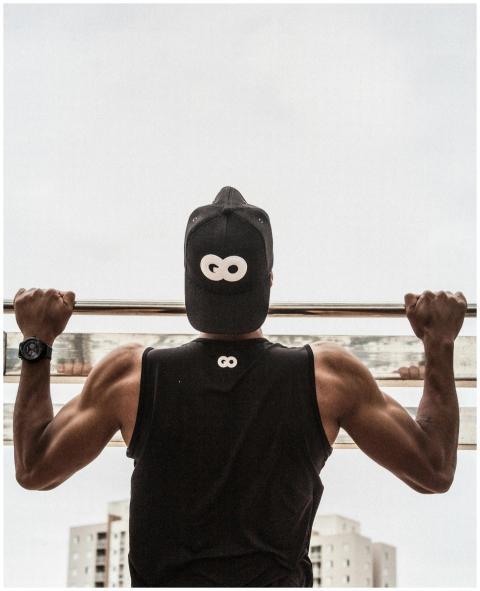 Back view of a man in gym attire doing pull-ups ou