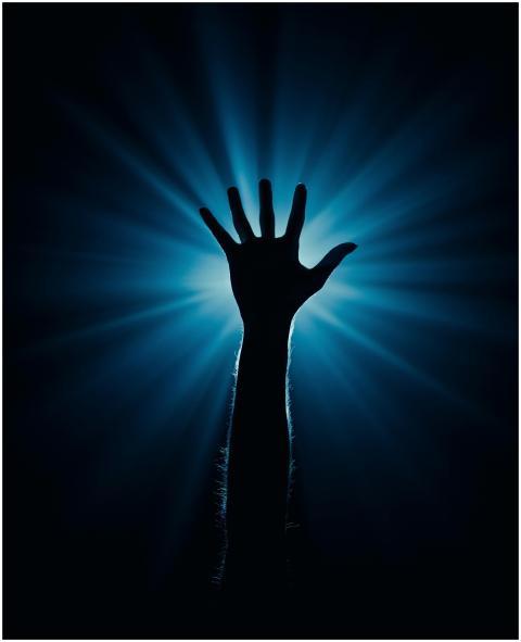 Silhouette of a hand reaching out with a dramatic