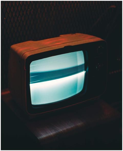 A vintage television glowing in a dark, retro ambi