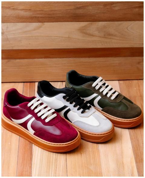 Three pairs of trendy sneakers on a wooden floor o