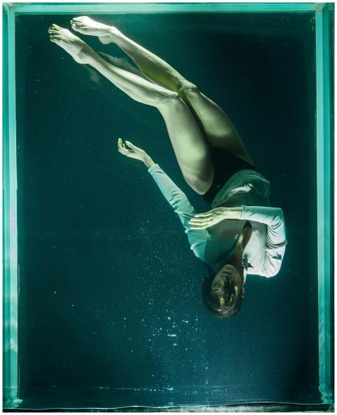 A woman gracefully poses underwater in a clear tan