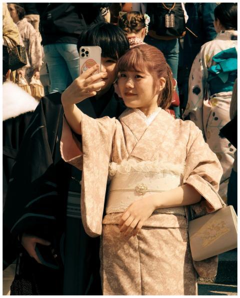 A young woman in a traditional kimono captures a s