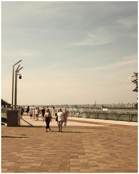 People enjoying a sunny day walking along a Kyiv r