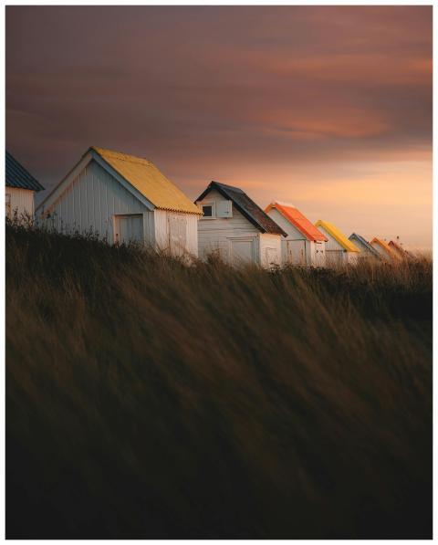 Vibrant beach huts with colorful roofs under a dra