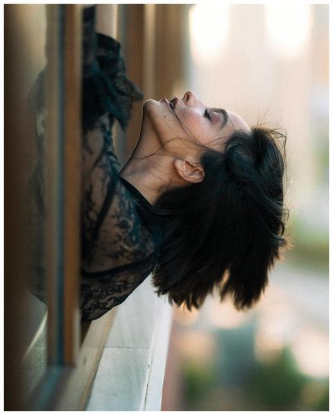 Artistic portrait of a woman leaning out a window