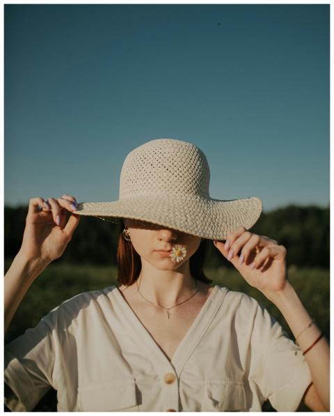 A young woman wearing a sun hat and holding a dais
